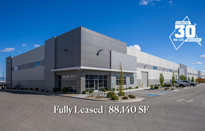 Modern industrial building with a glass entrance; text at bottom reads 'Fully Leased | 88,140 SF' against a clear blue sky.