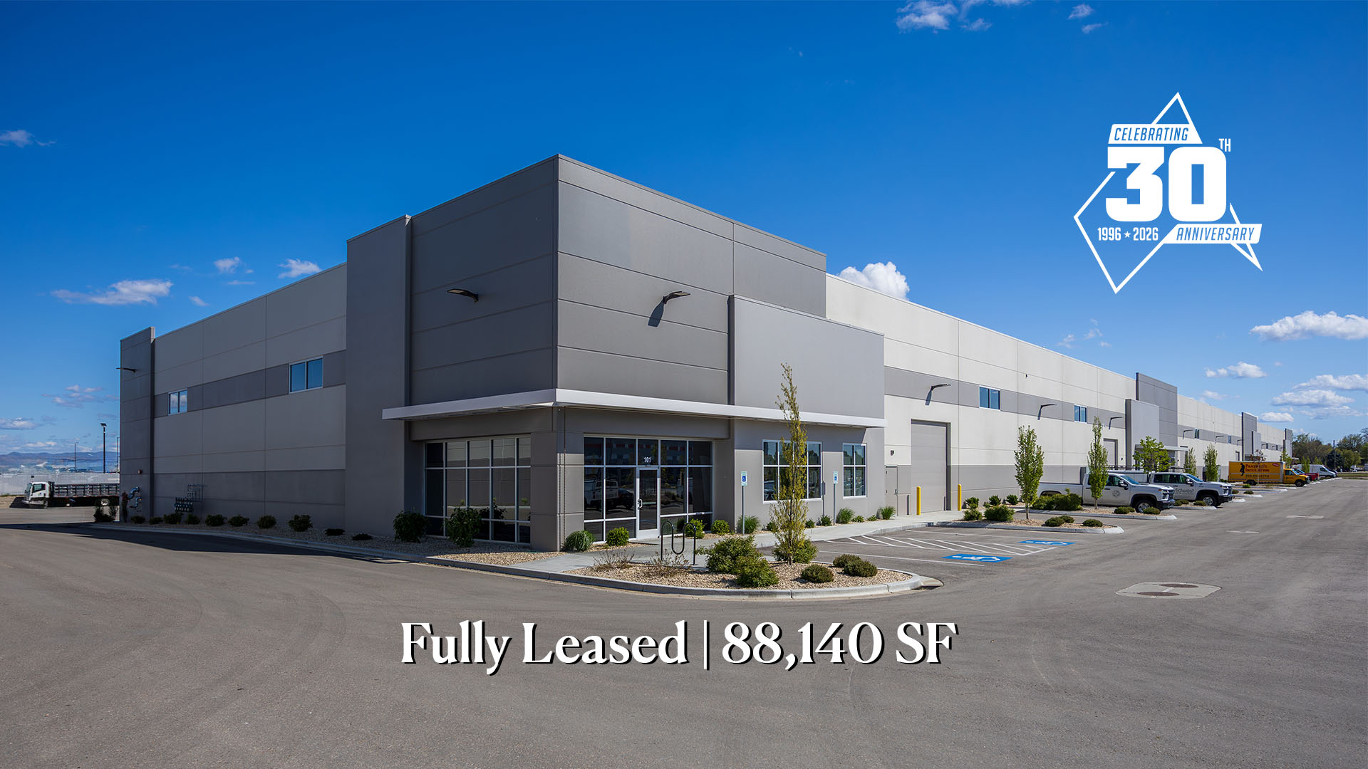 Modern industrial building with a glass entrance; text at bottom reads 'Fully Leased | 88,140 SF' against a clear blue sky.